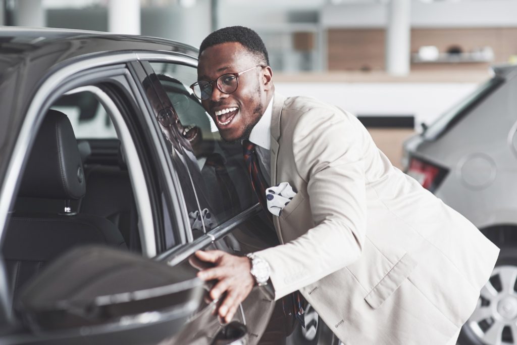 African man looking at a new car at the car dealership.
