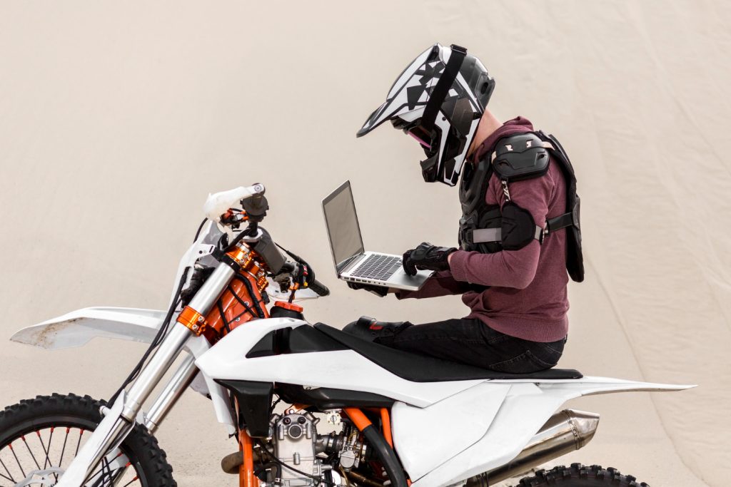 Motorbike rider browsing laptop in the desert